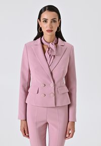 Lichtroze dubbel-breasted blazer met gouden ronde knopen, zakflappen en een bijpassende das, met een gestructureerd ontwerp en een gladde textuur.