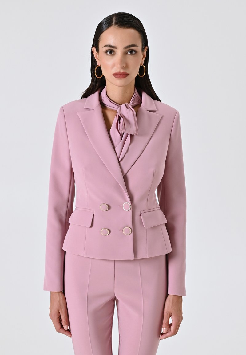 Lichtroze dubbel-breasted blazer met gouden ronde knopen, zakflappen en een bijpassende das, met een gestructureerd ontwerp en een gladde textuur.