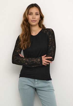 Black long-sleeve top with lace accents on sleeves, round neckline, and soft texture. Paired with light blue pants.
