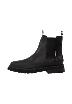Black leather ankle boots with elastic side panels, pull tabs, a stacked heel, and textured rubber sole. Features minimal branding on side.