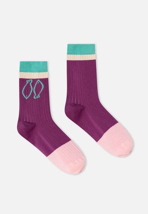 Chaussettes côtelées violet avec orteils roses, chevilles crème et bleu sarcelle, une chaussette avec deux motifs de poissons bleu sarcelle près de la cheville.