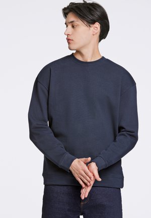 Marine crewneck sweatshirt lavet af blødt materiale med sænkede skuldre og ribbede manchetter. Enkel design uden mønstre eller yderligere accenter.