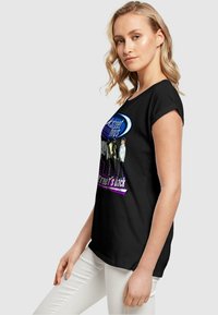 Sort t-shirt med rund halsudskæring og korte ærmer, med farverig grafisk tekst og billeder på forsiden. Glat stofstruktur.