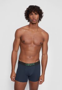 Dunkelblaue Boxershorts mit einem schwarzen Bund, der das grüne "Levi's"-Logo trägt. Glatte Stofftextur, eng anliegendes Design und mittellange Beinform.
