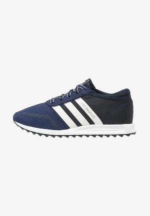 Zapatilla deportiva azul marino y negra con rayas blancas, texto "Los Angeles" en el lateral, suela blanca con suela exterior negra texturizada.