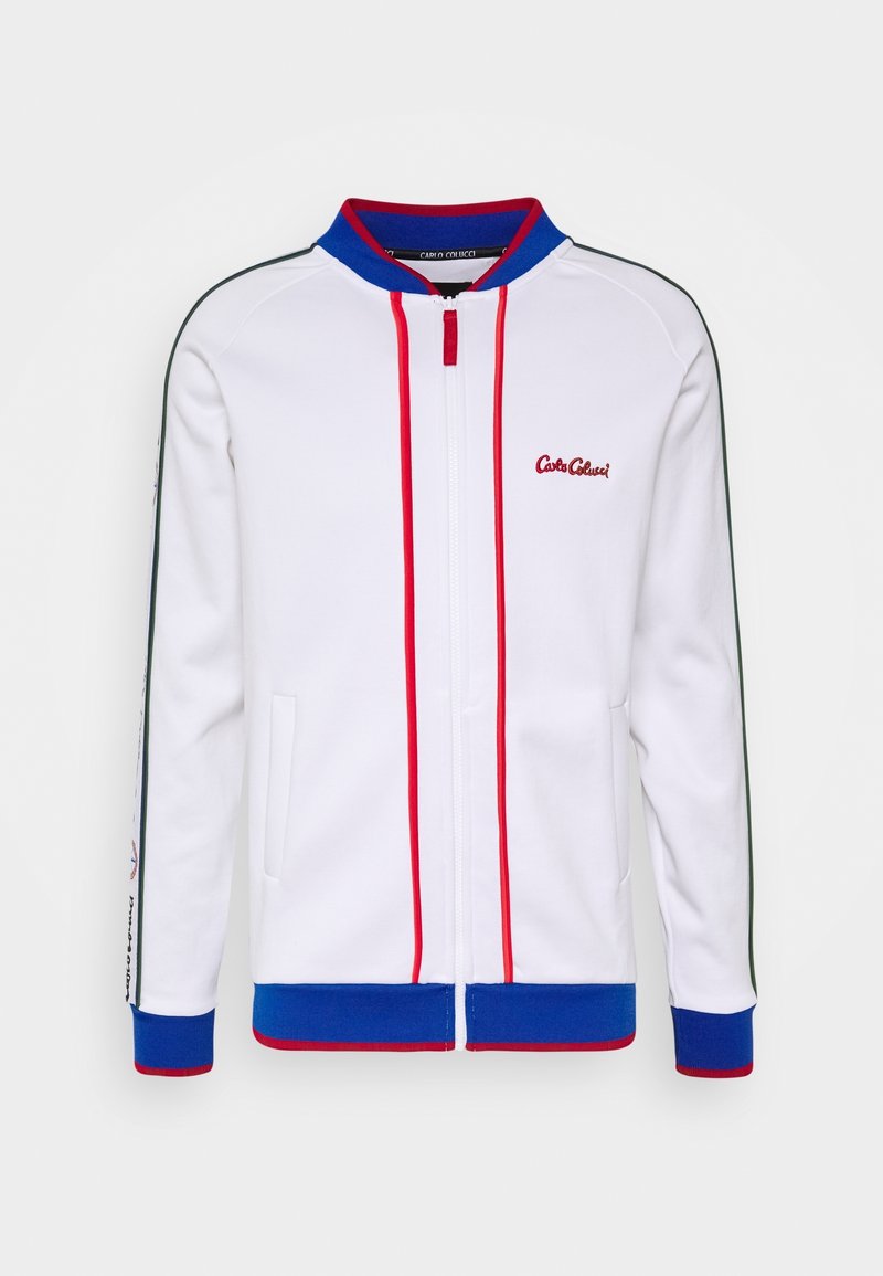 Veste blanche zippée avec bordures bleues et rouges, poches latérales et petit logo rouge "Carlo Colucci" sur la poitrine.