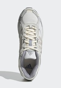 Fehér hálós sportcipő szürke részletekkel, párnázott nyelvvel és lapos fűzőkkel, texturált gumi talppal és Adidas logóval az oldalon.