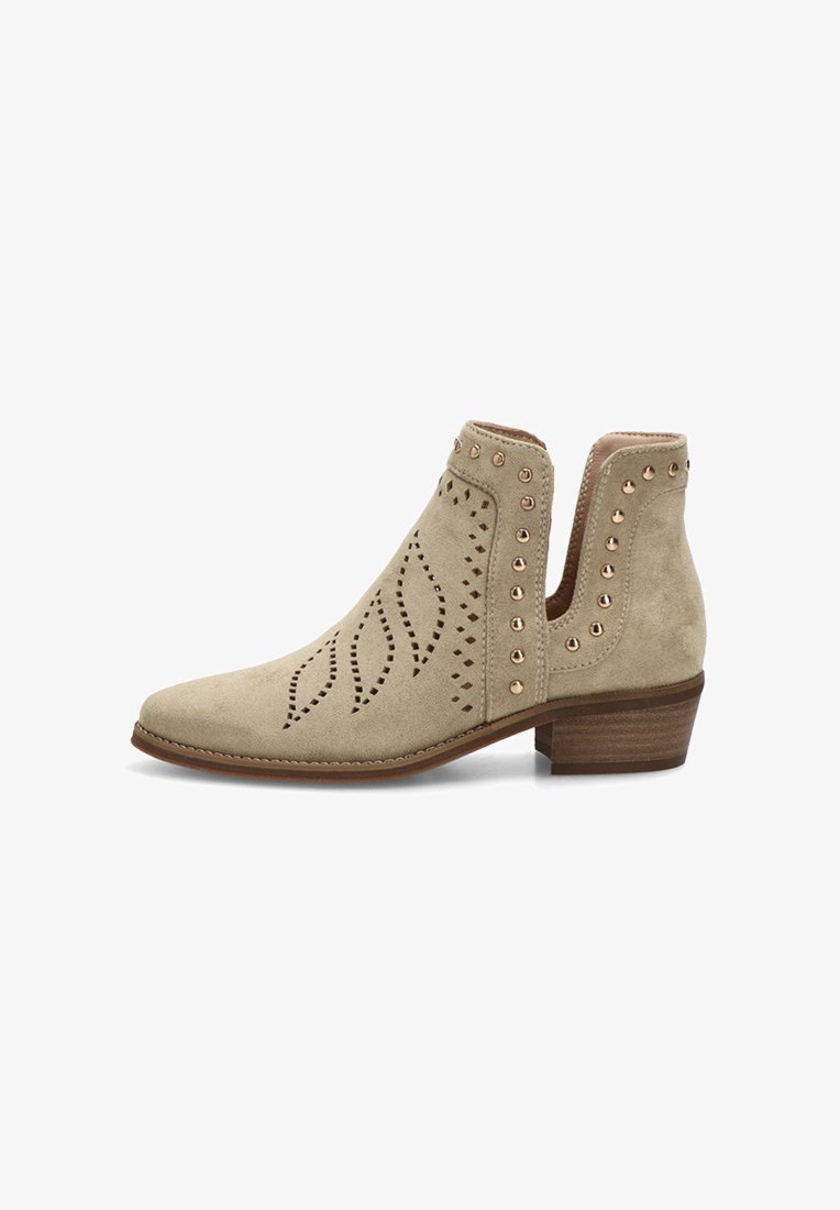 Botín beige de ante con patrones de hojas cortados con láser, tachuelas doradas a lo largo de la abertura y un tacón bajo apilado de madera.