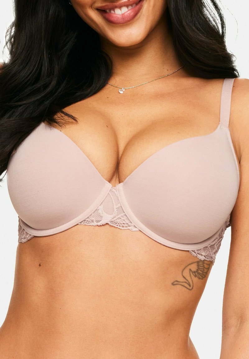 Soutien-gorge beige à dentelle, avec des bonnets moulés, des bretelles réglables, un tissu lisse et une forme courbée, conçu pour le soutien et le confort.