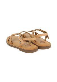 Sandales en cuir tan avec des sangles tressées, semelles plates et boucles réglables. Semelle intérieure rembourrée et semelle extérieure en caoutchouc brun.