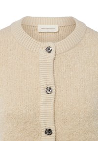 Beige gebreid vest met een gestructureerde afwerking, voorzien van een geribbelde kraag en drie decoratieve zilveren knopen aan de voorkant.