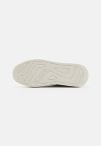Sole in gomma bianca con scanalature curve, caratterizzata dal logo "GUESS" stampato sul tallone e un motivo testurizzato per la trazione.