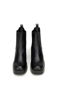 Botines de cuero negro con una textura suave, punta redondeada y paneles laterales elásticos. Con tiradores para ponérselos con facilidad y un tacón bajo tipo bloque.