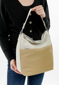 Bolso de cuero con una parte superior en crema y un panel inferior beige. Cuenta con un cierre de cremallera y una correa ajustable. Textura suave, diseño minimalista.