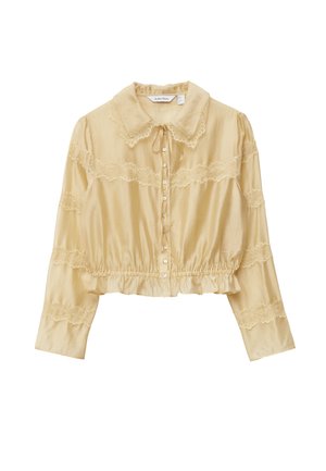 Cream blouse with a ruffled hem, long sleeves, lace accents, and a buttoned front. Features a pointed collar and ribbon tie at neckline.