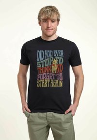Black t-shirt featuring multicolored text and a graphic of a bear holding a honey pot. Crew neck, short sleeves, made from cotton material.