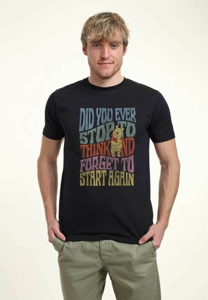 Svart t-shirt med flerfärgad text och ett grafiskt motiv av en björn som håller i en honungsburk. Rund hals, korta ärmar, tillverkad av bomullsmaterial.