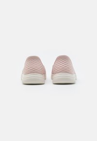 Zapatillas rosa slip-on con parte superior de malla texturada, que presentan una suela de goma blanca. La vista trasera muestra un cuello acolchado y bordes lisos y redondeados.