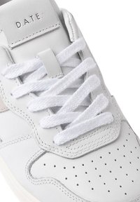 Hvide sneakers med lædermateriale, perforeret design, flade hvide snørebånd og diskrete grå accenter. Branding "D.A.T.E." på tungen.