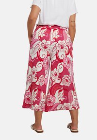 Blommönstrade rosa culotter med vida ben, tillverkade av lätt material. Har stora vita blommor och snirklingar i nyanser av rött och rosa.