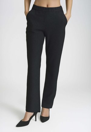 Pantaloni neri a vita alta realizzati in un tessuto liscio e texturizzato, con taglio dritto e tasche laterali, abbinati a tacchi a spillo neri.