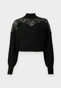Pull court noir avec col montant, doté de détails en dentelle sur les épaules et de manches longues. Étoffe en tricot doux.