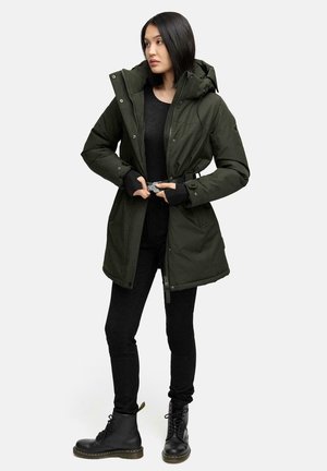 Gewatteerde groene parka met een capuchon, rits- en drukknoopsluiting, zijzakken en een verstelbare taille. Draagt over een zwarte top en zwarte broek met laarzen.