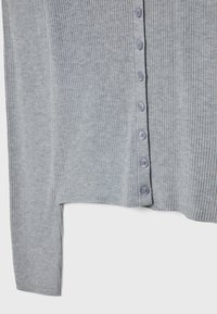 Szary prążkowany sweter z rzędem sześciu niebieskich guzików z przodu oraz krótkim fasonem i długimi rękawami.