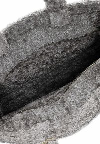 Pilka, tekstūruota audinio maišelis su minkštu, pūkuotu paviršiumi. Turėtų vidinį kišenę su užtrauktuku ir minkšta pamušalu. Du tvirti rankenai.