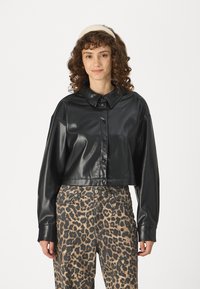 Svart cropped lærjakke med klassisk krage, knapper foran og lange ermer, sammen med høy midje bukser med leopardmønster.