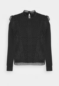 Mustat pitkät hihat -pusero, jossa on teksturoitu kangas kohonneilla pisteillä, monimutkainen pitsikoristelu sivuilla ja aaltoileva kaula-aukko.