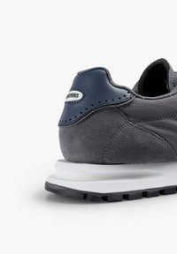 Graue Sneaker mit Obermaterial aus Wildleder und Mesh, akzentuiert mit navyblauen Lederdetails und einer weißen Zwischensohle. Verfügt über eine strukturierte Oberfläche und eine gerippte Gummisohle.
