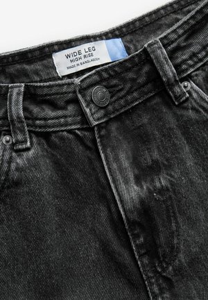 Wide leg high-rise jeans in dark gray denim. Features a button closure and visible stitching. Label indicates country of manufacture: Bangladesh.