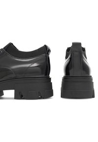 Pantofi negri din piele lăcuită cu o talpă din cauciuc negru masiv, având un guler pentru gleznă ribatat și detalii de design minimaliste.