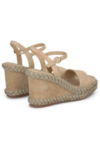 Sandalias de cuña beige con diseño de tiras cruzadas, tejido texturizado y acento de cuentas a lo largo del borde del tacón de cuña. Plantilla suave.