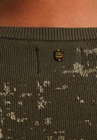 Groene gebreide trui met een ribbelontwerp en een lichte gespikkelde print. Kenmerkt zich door een zwart label met "PME Legend" op de halslijn.