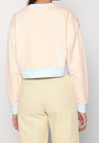 FELPA CORTA PESCA CON COLLETTO RIGATO BLU, CON UNA TEXTURA MORBIDA. ABBINATA A PANTALONI IN CORDUROY BEIGE CON TASCA POSTERIORE.