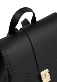 Black leather handbag with top handle and gold rectangular clasp, showing smooth texture and detailed stitching.