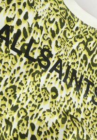 Tessuto leopardato giallo e verde con scritte nere che dicono "ALLSAINTS." Superficie testurizzata con motivi e colori contrastanti.