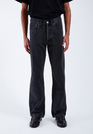 Black denim jeans with a straight-leg design, five pockets, and copper hardware accents, featuring a mid-rise waist and subtle texture.