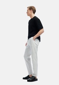 Zwarte gestructureerde shirt met korte mouwen, lichtgrijze op maat gemaakte broek en zwarte gespschoenen. Eenvoudig, modern ontwerp met een relaxte pasvorm.