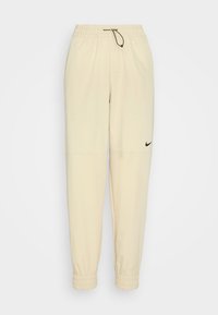 Light beige Nike jogger pants made from soft fabric, featuring an elastic waistband with drawstring, side pockets, and cuffed ankles.