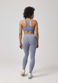 Senza maniche grigia chiara con design a schiena scoperta abbinata a leggings aderenti a vita alta, caratterizzati da una texture sottile e una forma su misura.