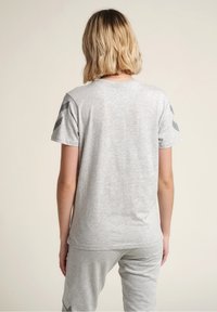 Szary t-shirt z krótkim rękawem i okrągłym dekoltem, z ciemniejszymi szarymi akcentami na ramionach. Miękka tkanina i luźny krój.