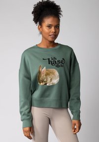 Groene sweatshirt met een grafisch ontwerp van een slapende konijn en zwarte tekst die luidt "ich haso dich." Standaard pasvorm met ribgebreide manchetten en zoom.
