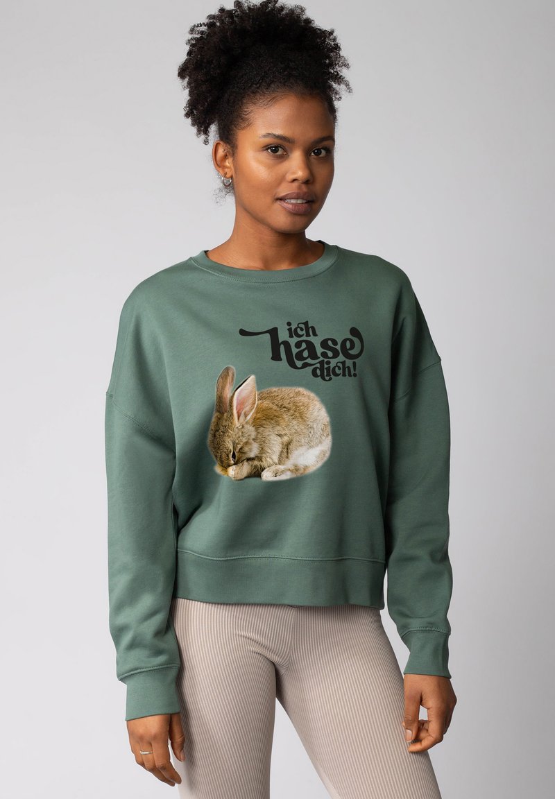 Groene sweatshirt met een grafisch ontwerp van een slapende konijn en zwarte tekst die luidt "ich haso dich." Standaard pasvorm met ribgebreide manchetten en zoom.