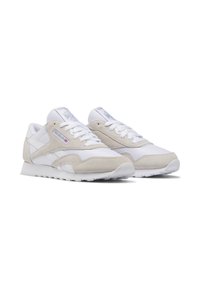 Valged ja beezid Reebok spordijalatsid, millel on nubukist lisad, valged lipsud ning logod küljel ja keele peal, kaldus paremale.