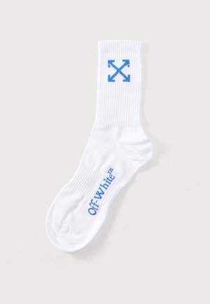 Chaussette blanche côtelée à tige courte avec logo Off-White bleu sur le pied et motif flèches croisées bleu près du bord-côte.