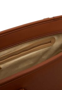 Interno di borsa in pelle marrone con fodera in tessuto beige e una tasca con cerniera su un lato.