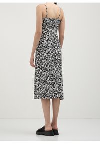 Šaty s leopardím potiskem v černobílé barvě s tenkými ramínky a elastickým korzetem. Sukně do délky ke kolenům s volným střih a nošena s černými platformovými sandály.